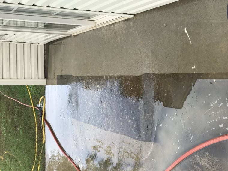 Concrete walkway partway through cleaning, showing the line between cleaned and uncleaned surface