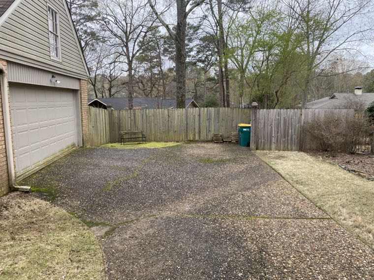 Exposed aggregate driveway darkened with moss and dirt before cleaning