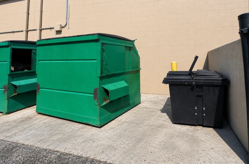Dumpster enclosure and pad against a commercial building