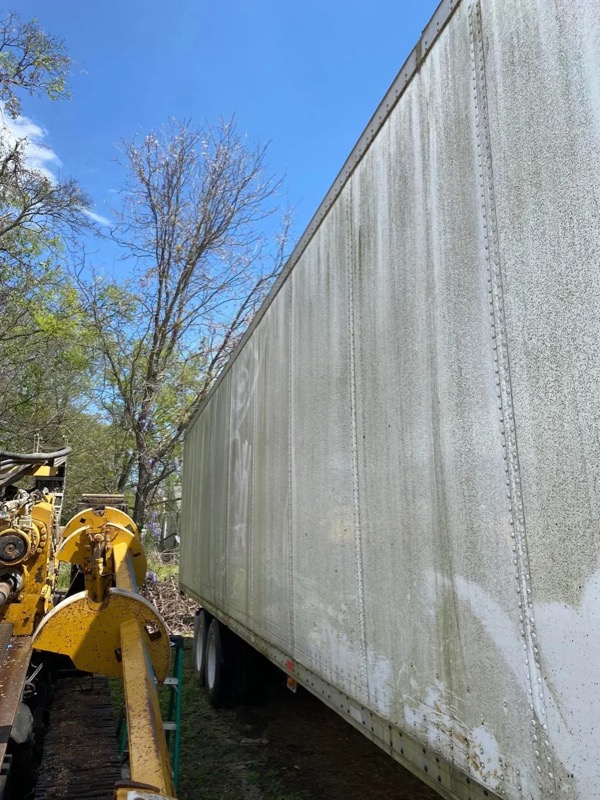 Box trailer with heavy green algae and road grime before washing