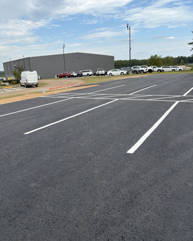 Freshly striped parking stalls on new asphalt beside a commercial building